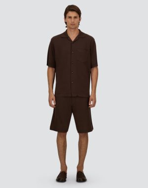 Man modeling a brown short-sleeve button-up shirt and matching shorts with loafers.