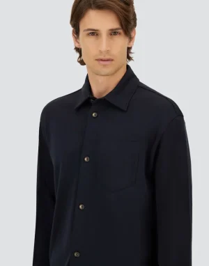Man wearing a dark navy button-down shirt with a collar and chest pocket, posed against a light gray background.