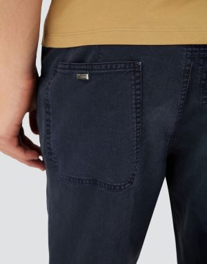 Back view of dark denim jeans with a large back pocket and a small metal brand tag on the pocket.