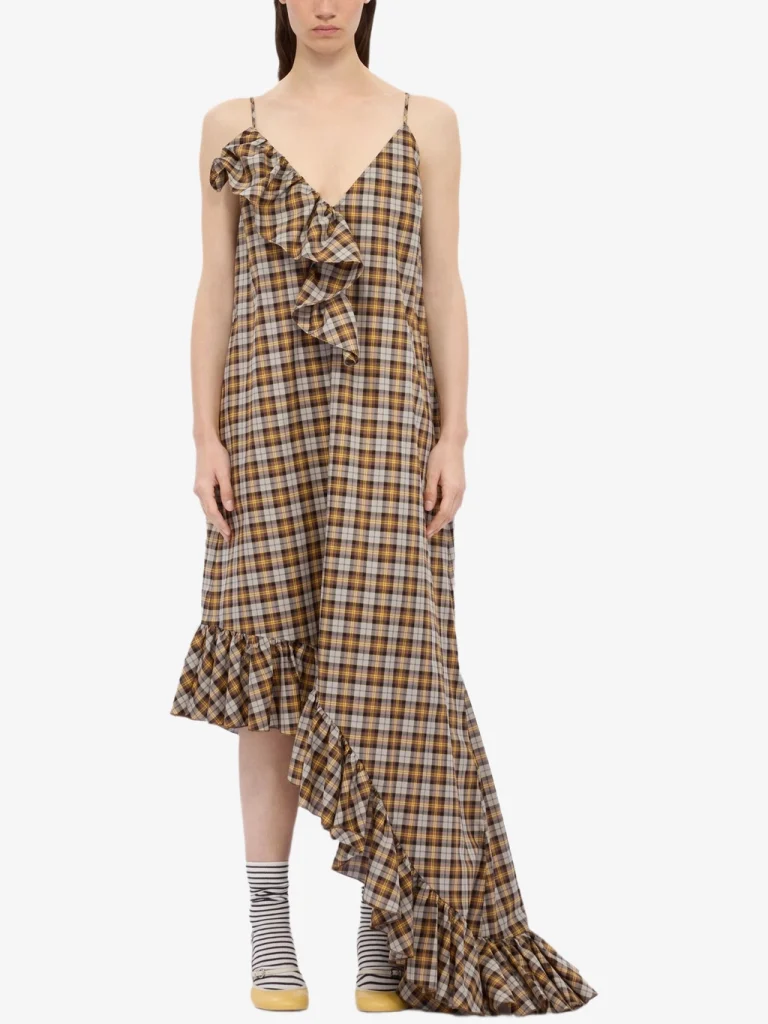Model wearing a brown and yellow plaid spaghetti-strap dress with a dramatic front ruffle and a high-low, ruffled hem.