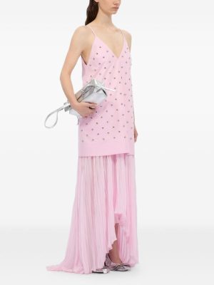 Model wearing a pink sleeveless tunic with bead embellishments over a sheer pink maxi skirt, holding a silver clutch.