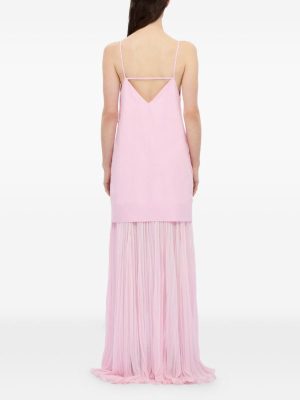Back view of a woman in a light pink spaghetti-strap dress with a V-back and a long pleated sheer skirt reaching the floor.