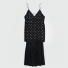 Black sleeveless dress with pearl embellishments, V-neck and spaghetti straps, paired with a sheer, layered skirt.
