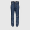 Blue denim jeans with a decorative crescent pattern along the lower legs, front view.