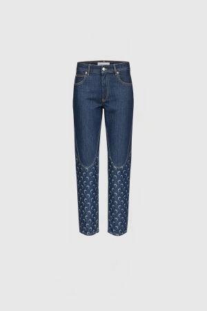 Blue denim jeans with a decorative crescent pattern along the lower legs, front view.