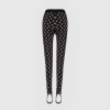 Waist-to-toe view of a mannequin wearing black leggings with a cream crescent pattern on a light gray background.