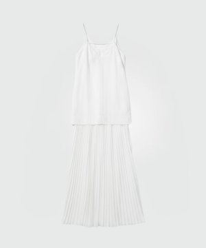 White sleeveless camisole top with thin straps paired with a long white pleated skirt against a light background