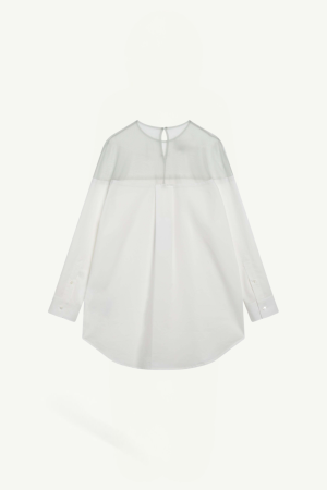 White blouse with sheer yoke and long sleeves, buttoned cuffs, and a small keyhole opening at the neckline