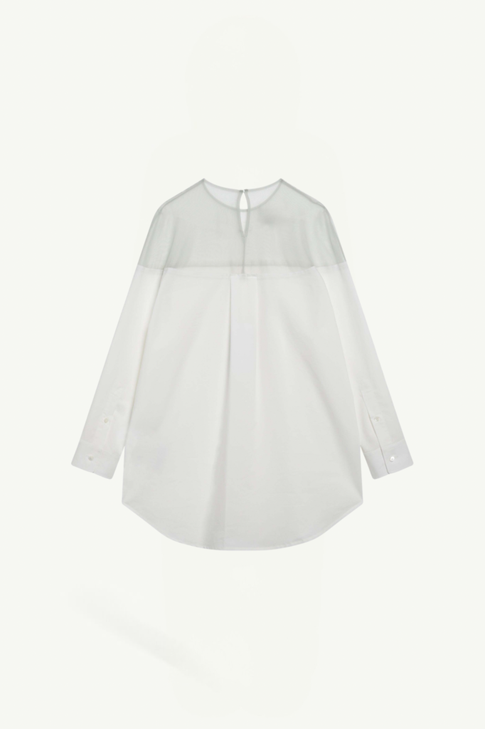 White blouse with sheer yoke and long sleeves, buttoned cuffs, and a small keyhole opening at the neckline