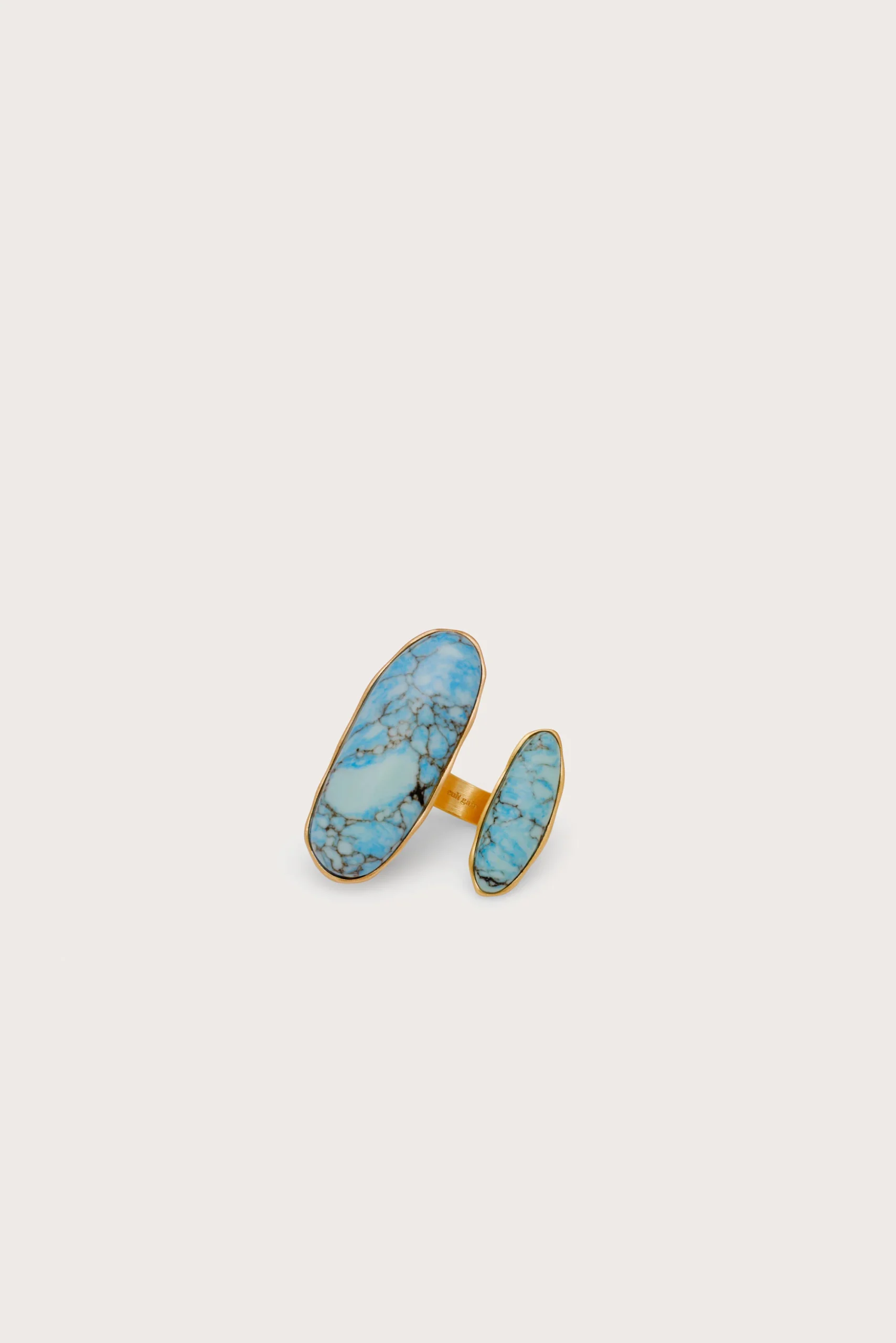 Gold-plated jewelry set with blue turquoise stones arranged as two long oval pieces and a matching band on a pale background