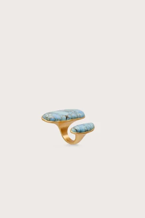 Gold ring with two turquoise stones set in a curved, open band against a pale background.