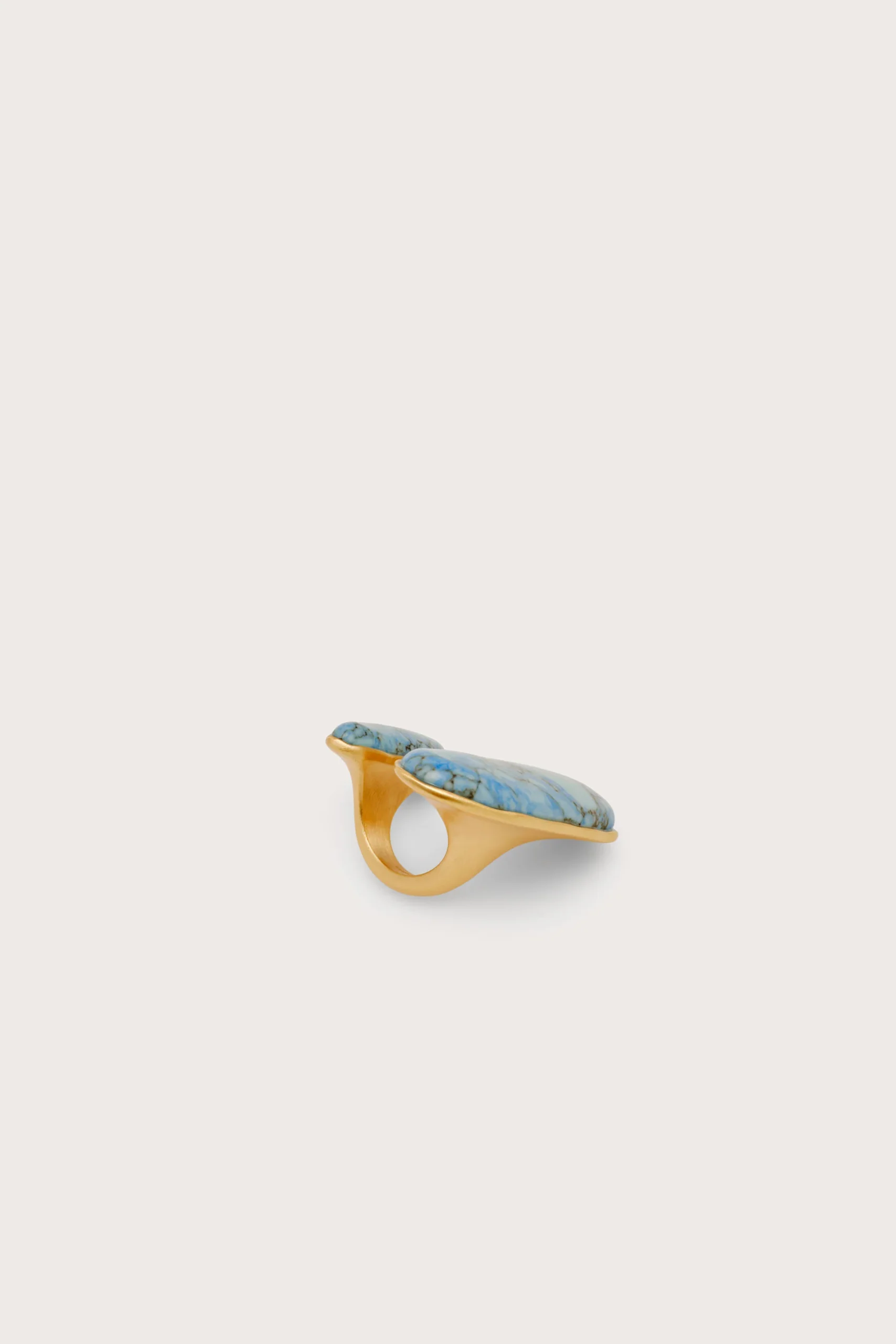 Gold-toned open cuff bracelet featuring two turquoise stones set along the top edge, shown at an angle on a light background.