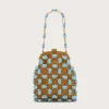 Beige background with a brown beaded handbag covered in turquoise stones and a matching turquoise bead handle chain.