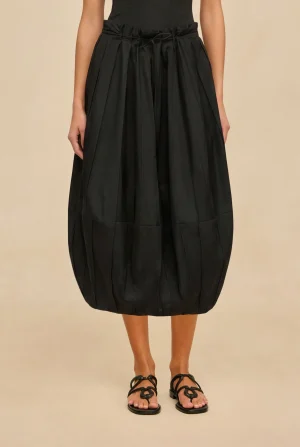 Black gathered midi skirt with a waist tie, worn with strappy flat sandals on a neutral background.