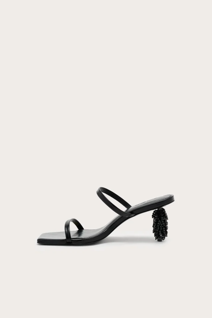 Black strappy sandal with a beaded, cylindrical heel on a pale background