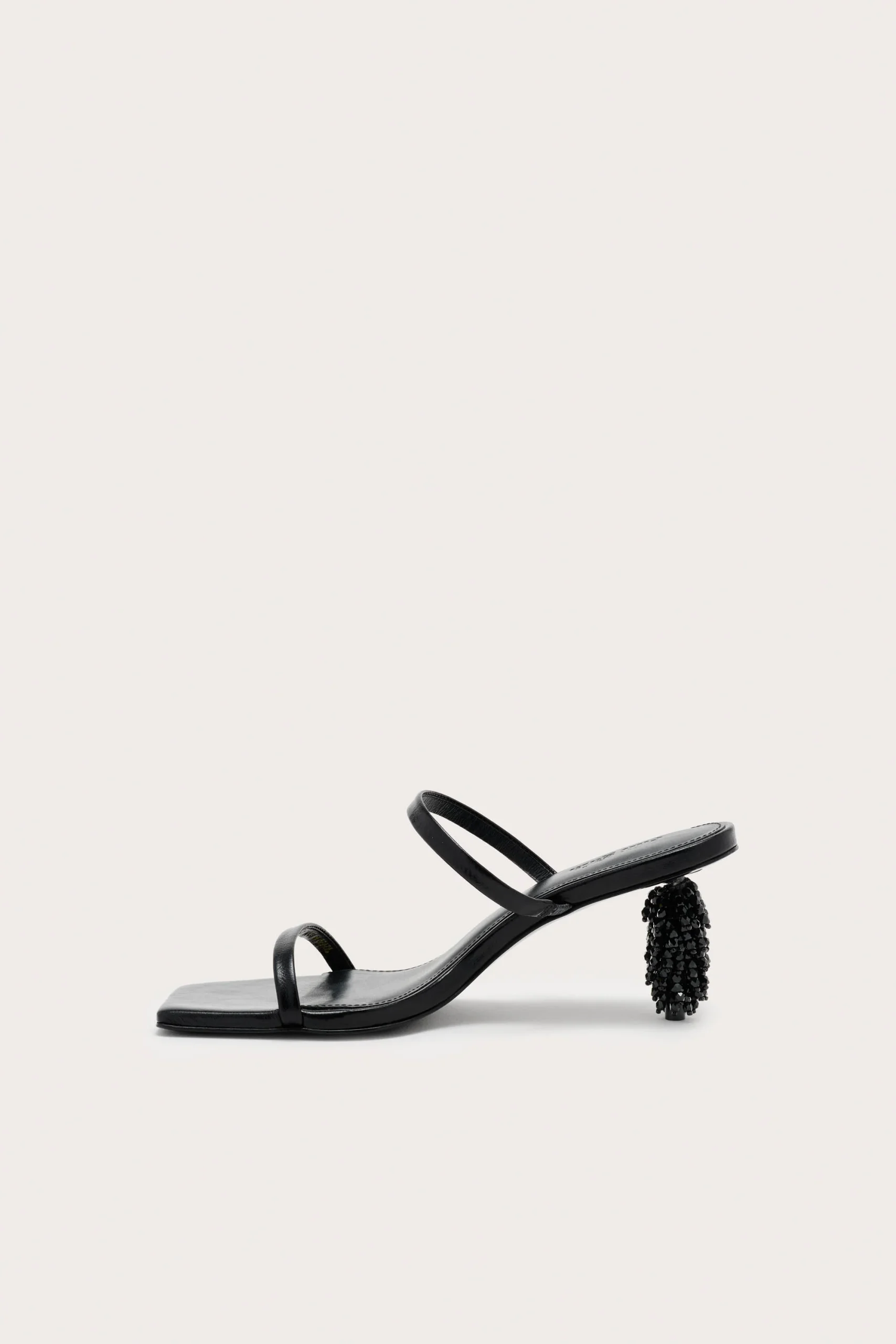 Black strappy sandal with a beaded, cylindrical heel on a pale background