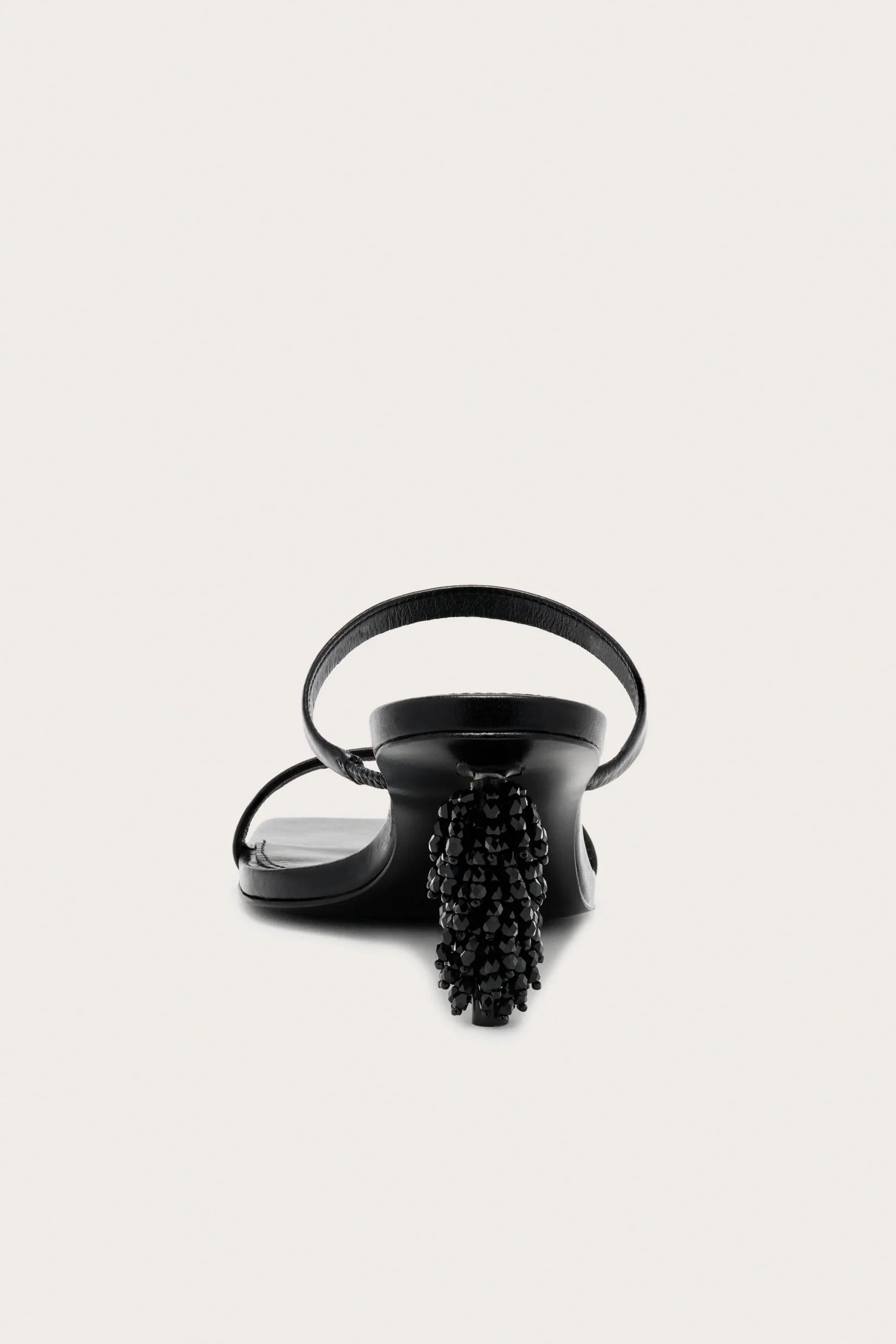 Black strappy sandal with a high beaded heel, pictured against a pale background.