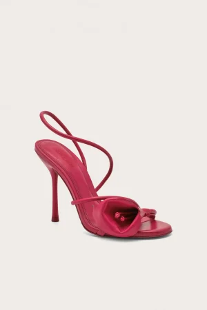 Pink high-heeled sandal with thin straps, shown from a side angle against a light background.
