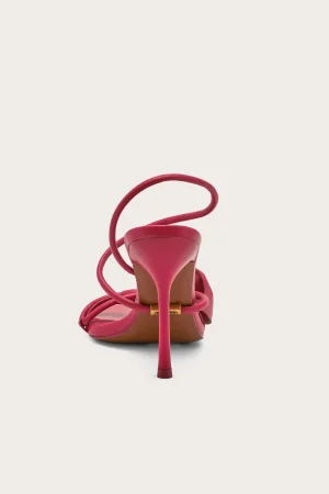 Pink high-heeled sandal shown from the back with curved straps and gold buckle, sandal in a bold fuchsia shade.