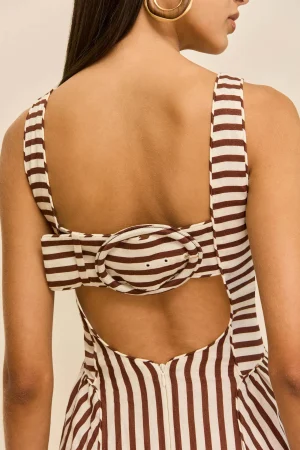 Back view of a woman wearing a brown-and-white striped top with a tied bow at the back and a gold hoop earring