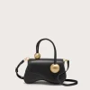 Black leather handbag with gold spherical hardware on each handle, set against a pale background.
