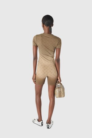 Back view of a person in a tan matching athletic set with a patterned texture, holding a beige handbag