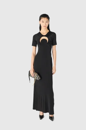 Model wearing a black floor-length dress with a circular cutout at the chest, holding a patterned clutch.