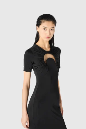 Model wearing a black dress with a ruched circular chest cutout, against a light gray background.