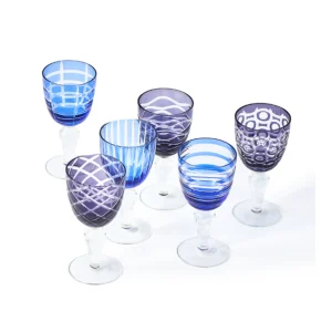 Colorful blue and purple patterned goblets and wine glasses arranged on a white surface.